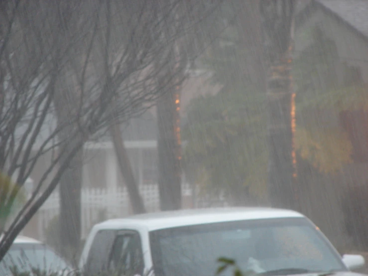 cars sit on the side of a street in the rain