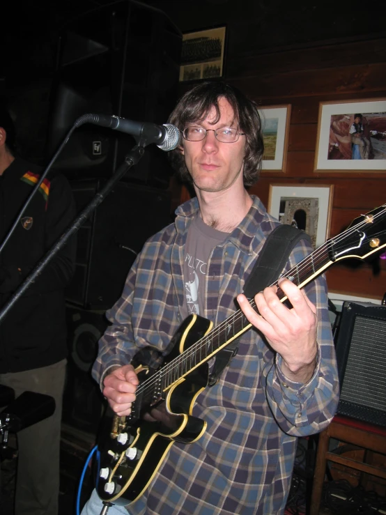 a young man with long hair and glasses plays an electric guitar