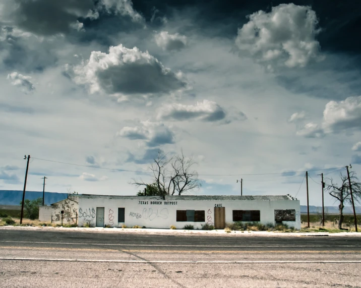 a white building on a side road and trees