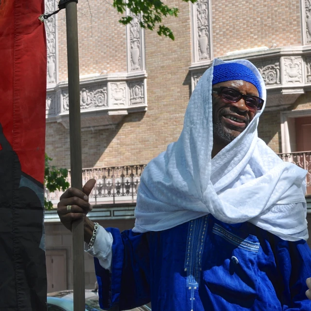 a man in a blue robe and headscarf holding a flag