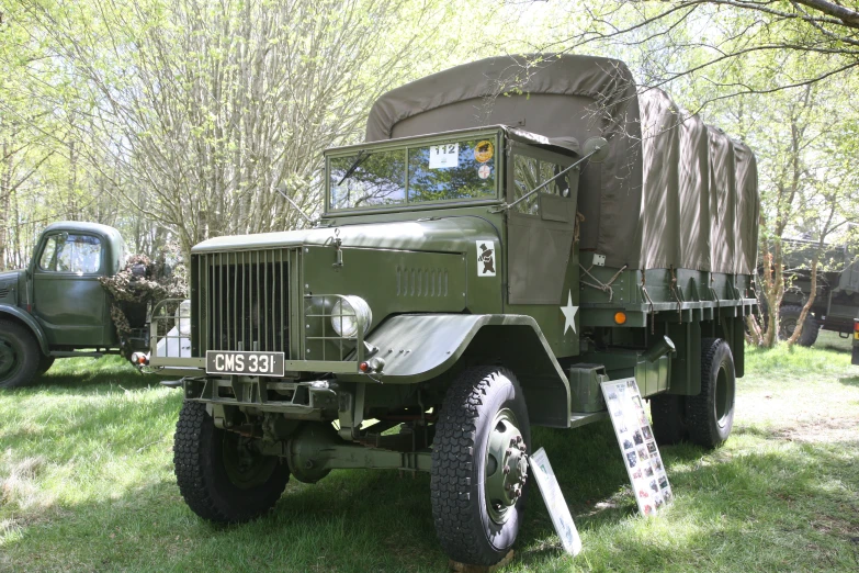 two old military vehicles and some green trees