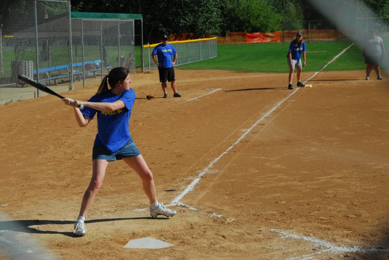 the female baseball player is about to hit a pitch