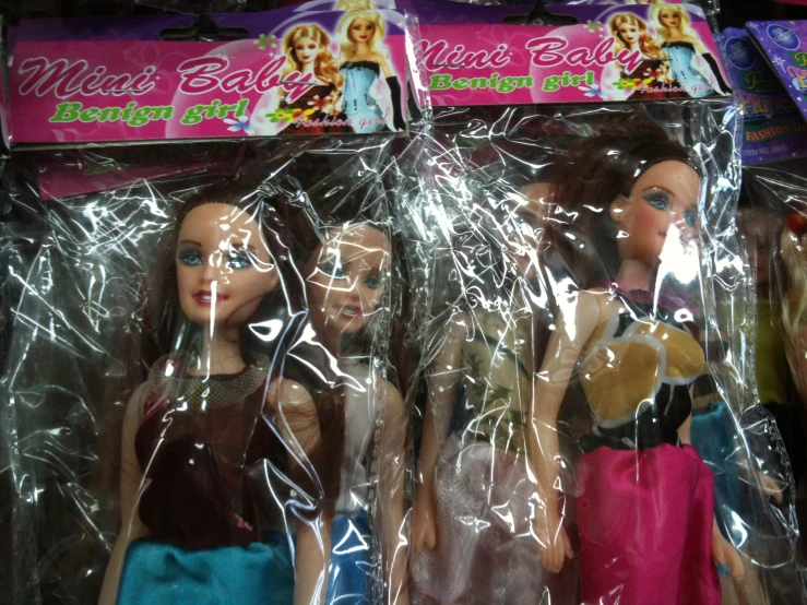 four dolls that are sitting in plastic wrappers