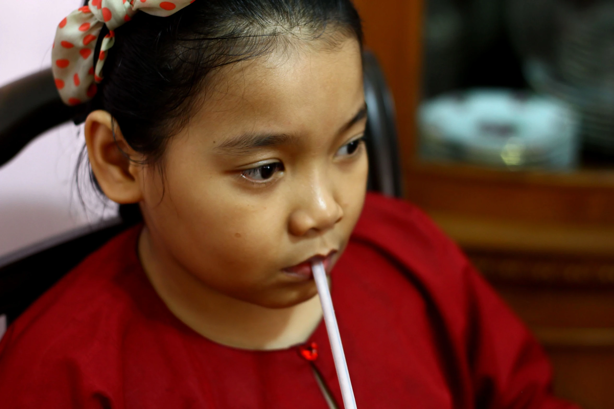 a  with a bow holding a straw in her mouth