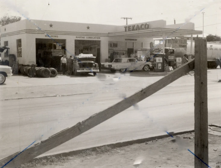 black and white pograph of a gas station with cars outside