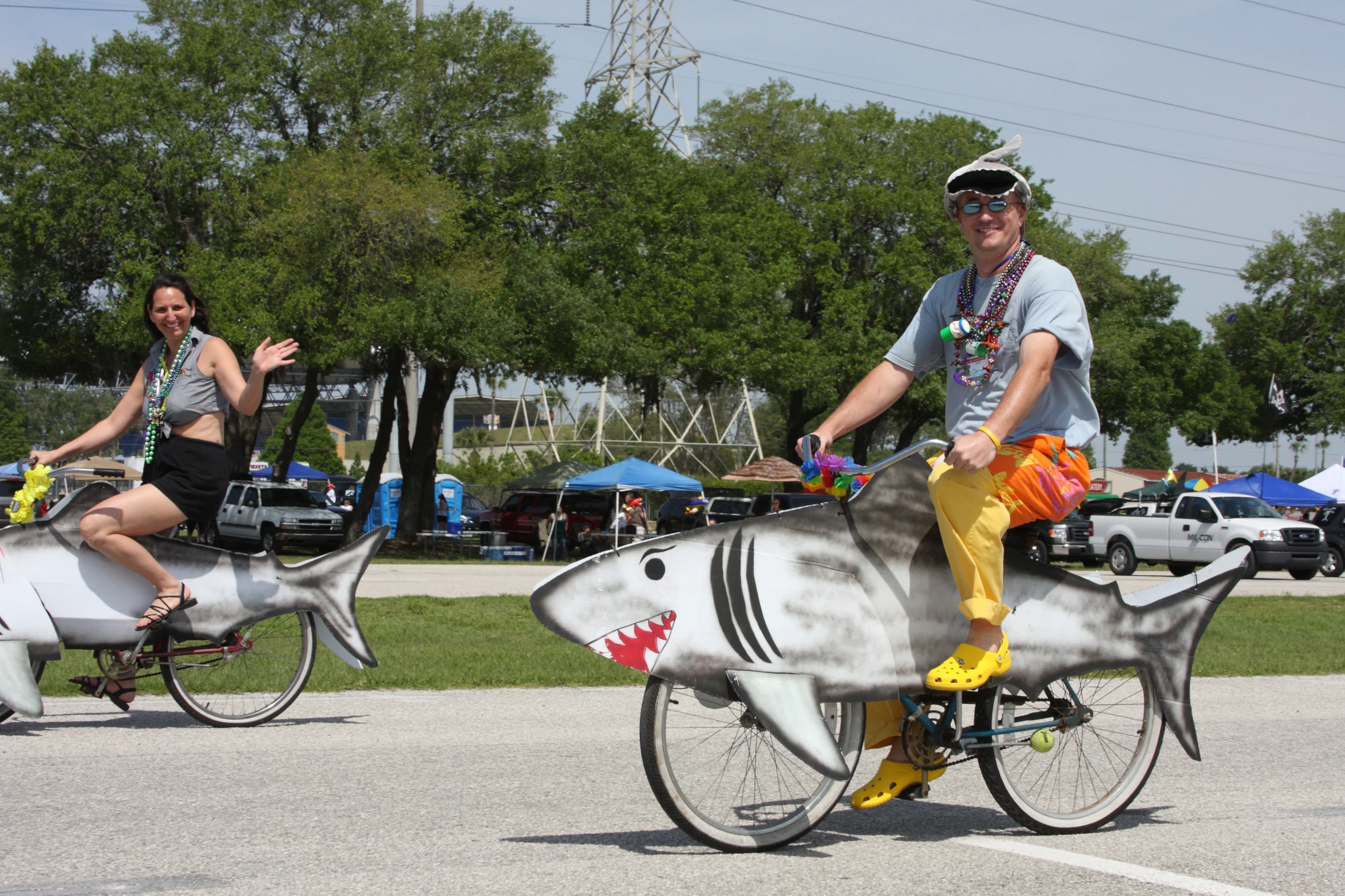 two people are riding bikes in front of a shark statue