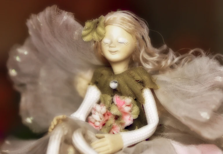 a doll wearing a dress holding a bouquet of flowers