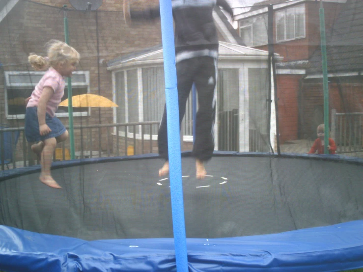 man and little girl in a backyard playing on a trampoline
