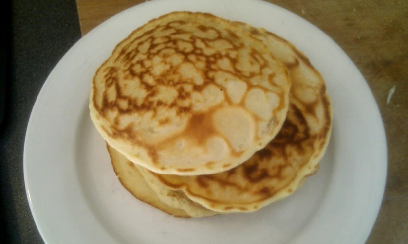 three pancakes sitting on a white plate covered in chocolate