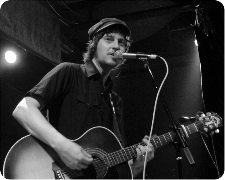 a man standing in front of a microphone holding a guitar