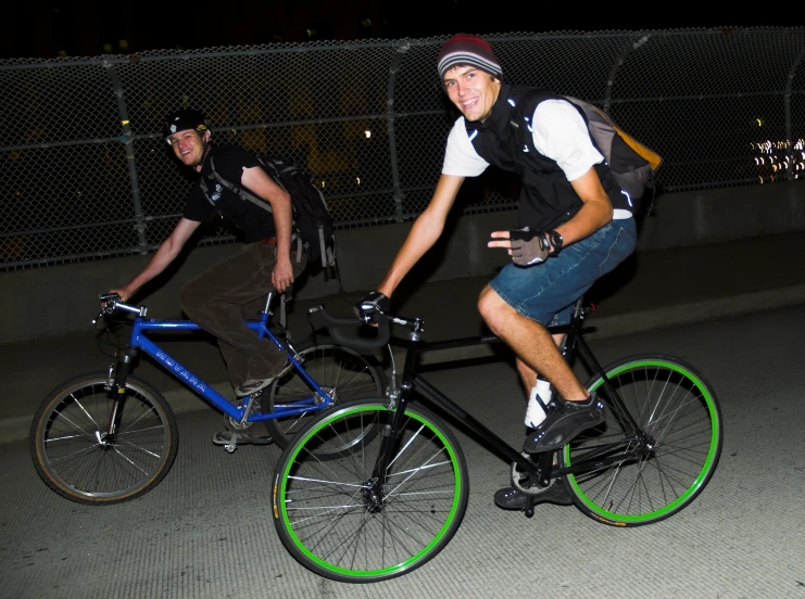 two men riding bikes together in the night