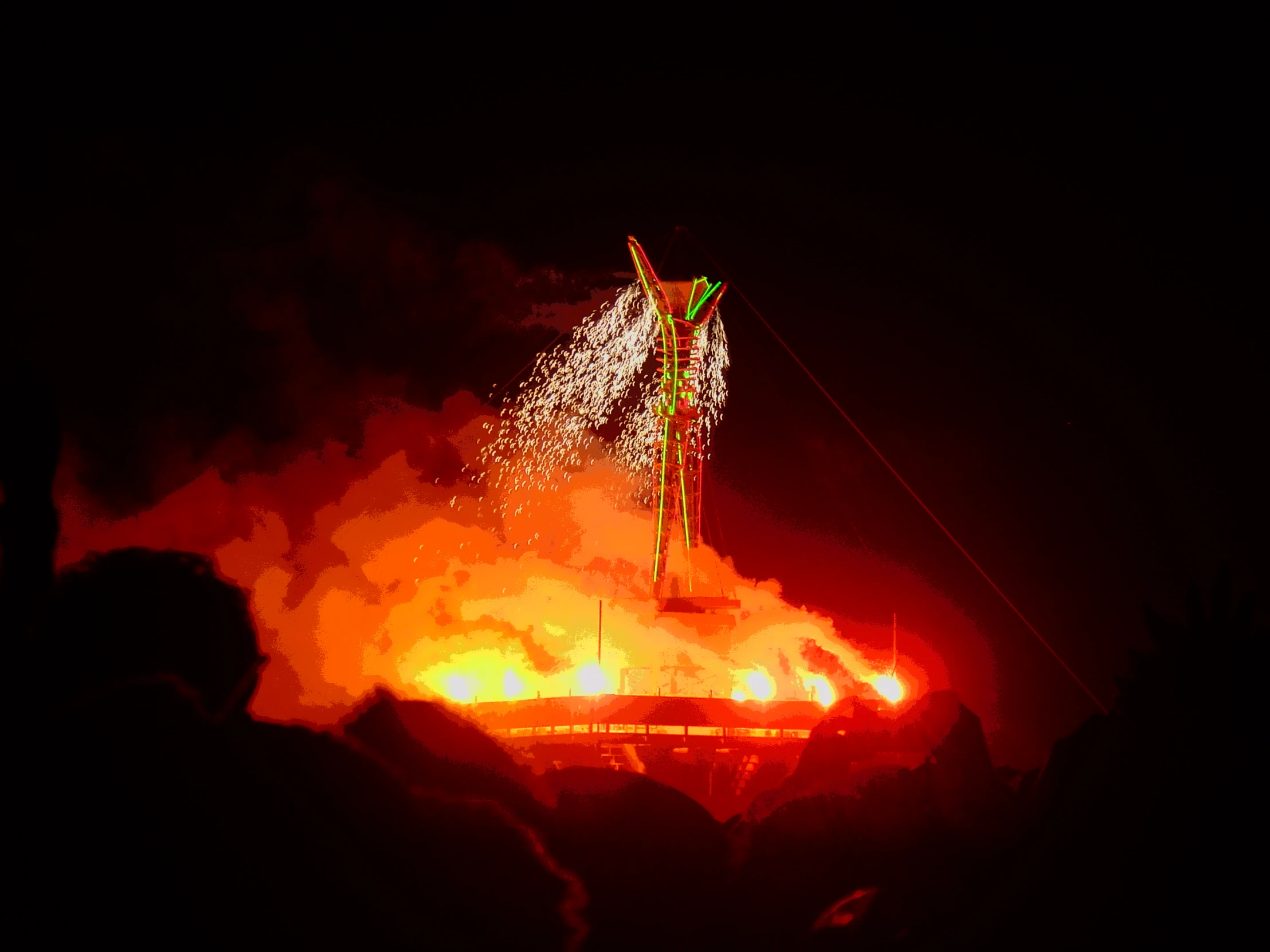 people watching a large fire and fireworks display