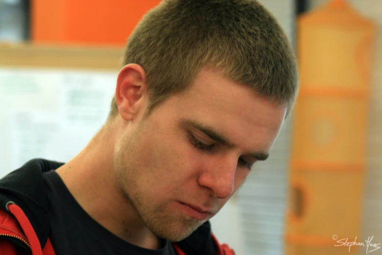 a man with dark hair and a black shirt looking down