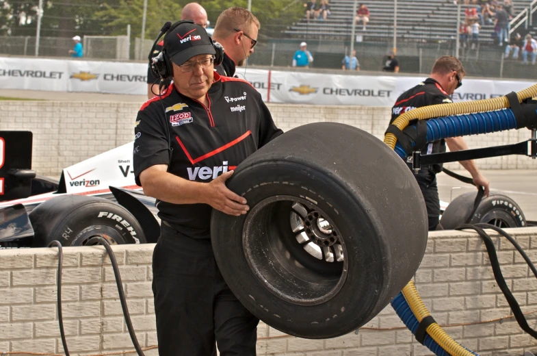 the mechanics stand by the tire in preparation for race