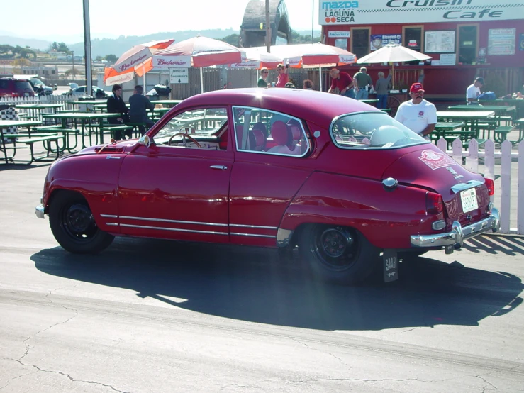 a red classic car sitting on top of a road