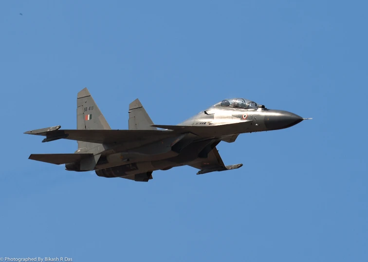 a grey military aircraft flying in a blue sky