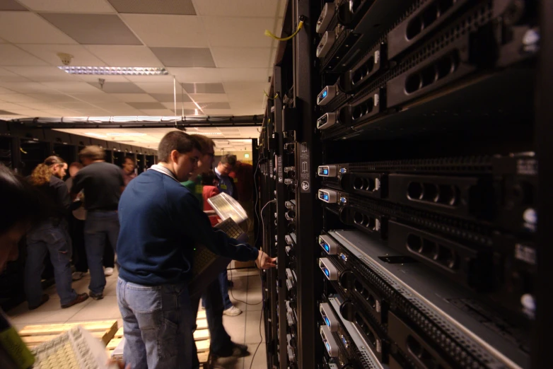 a man picking up items from a rack of servers