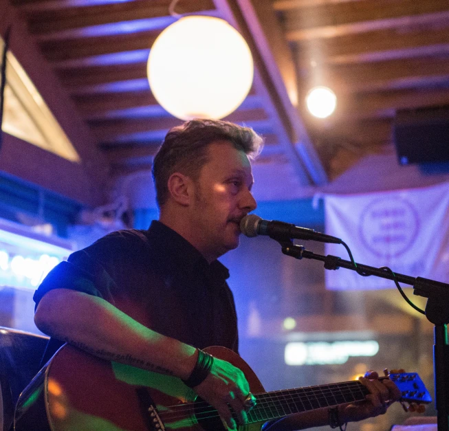 a man holding a guitar in front of a microphone