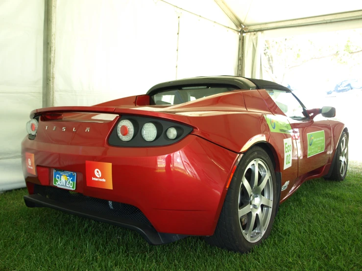 the back end of a red sports car with a sticker on it's hood