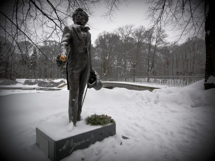 statue stands on a mound of snow at the base of a tree