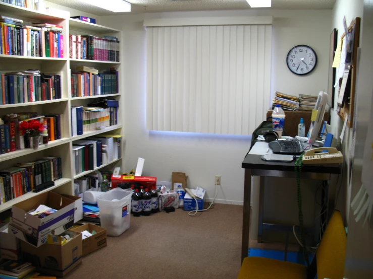 a bookshelf filled with lots of books sitting next to a wall mounted clock