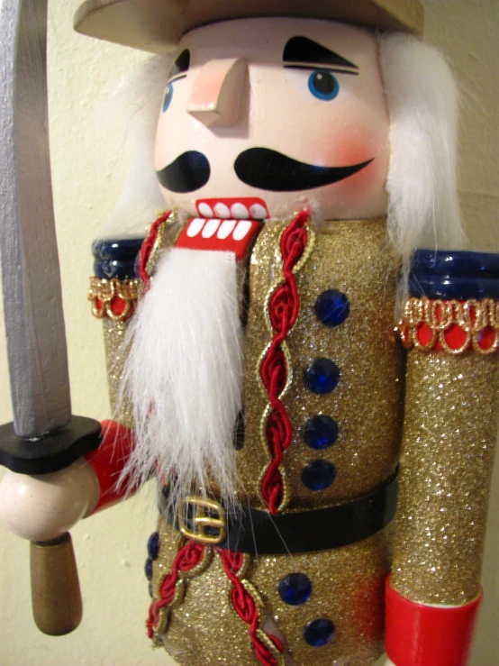 a nutcrier dressed in gold and red holds a sword