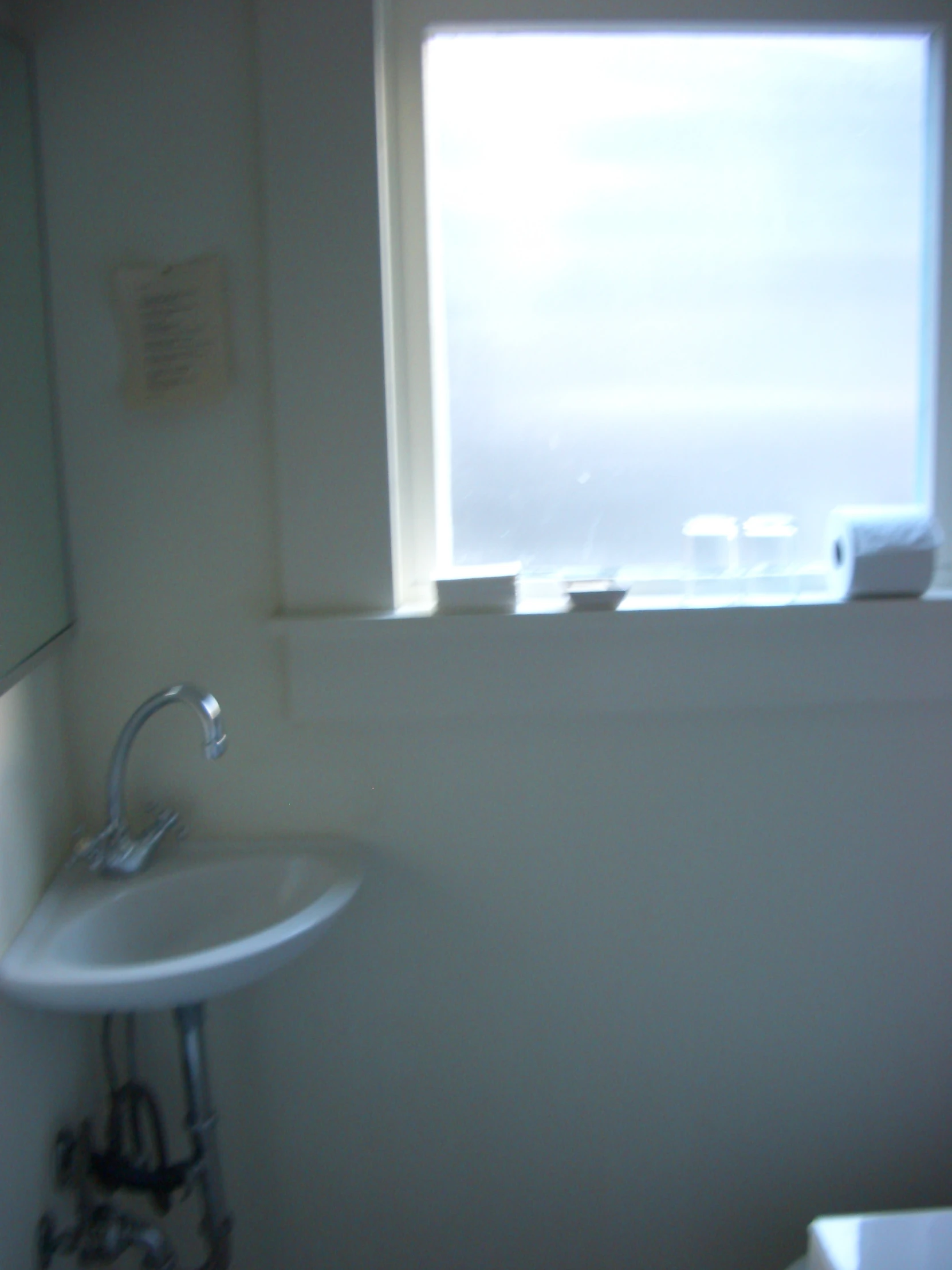 a bathroom with an open window and white sink