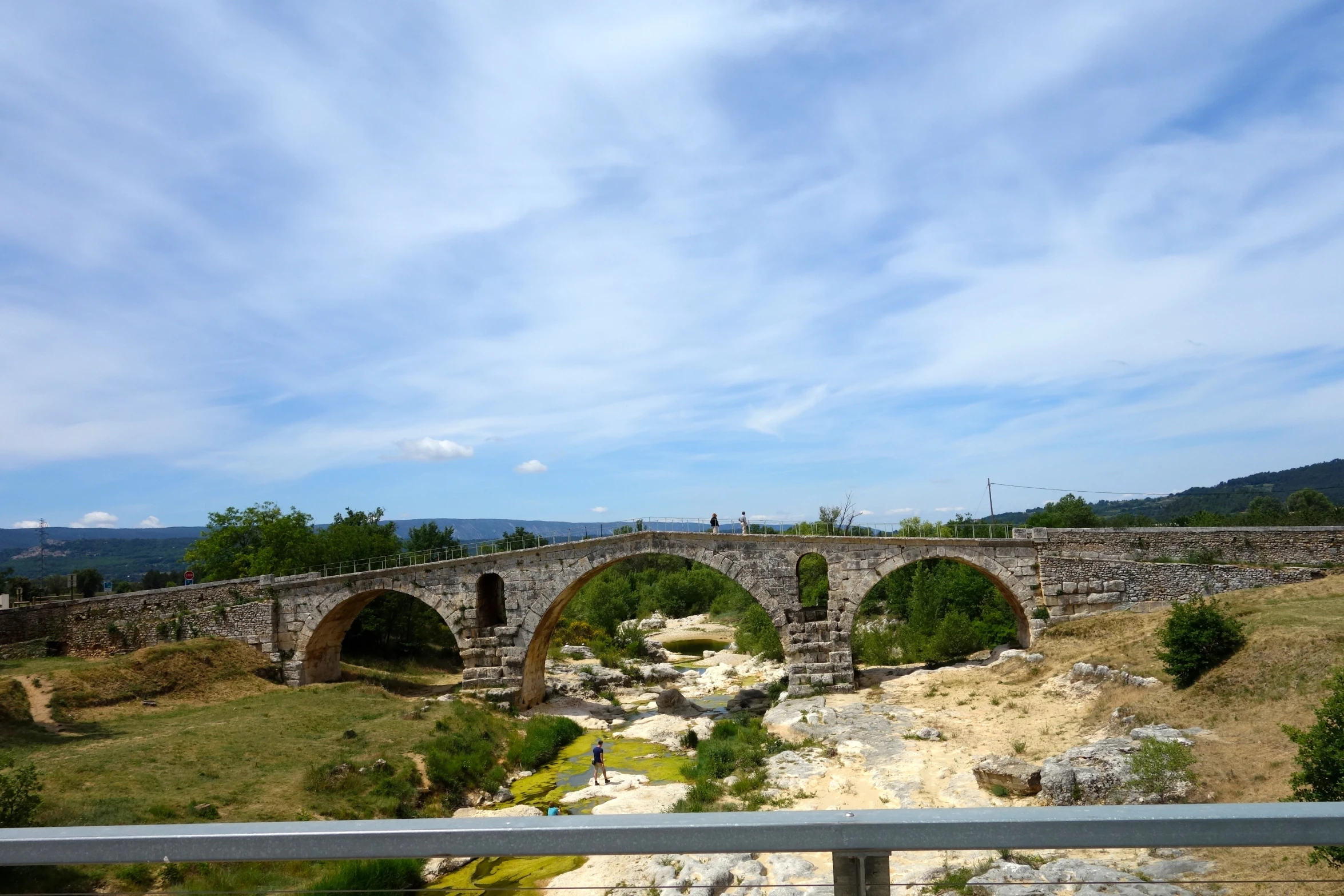 an ancient stone bridge surrounded by grassy hills