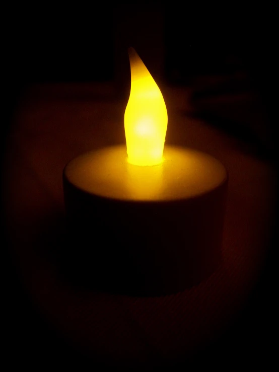 a lit candle on a table in the dark