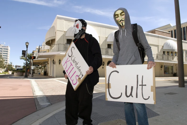 two men wearing masks, one holding a cut sign while the other holds a no enter sign