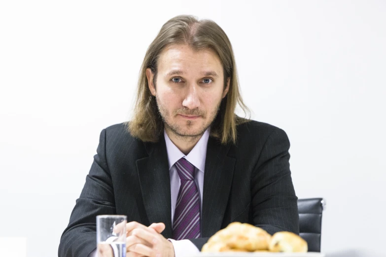 a man in a suit and tie sitting at a table with a plate of food