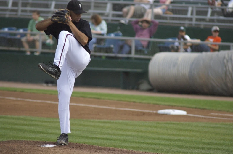 man in black shirt and white baseball uniform throwing a pitch