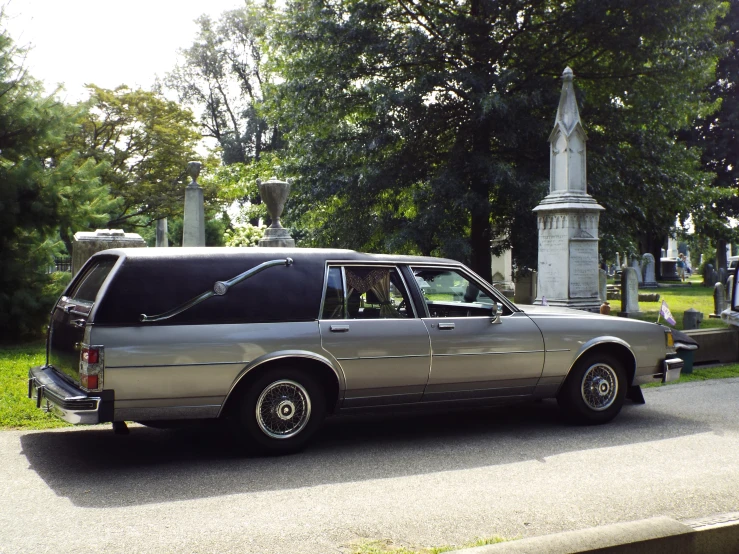 a silver hears sits in front of a cemetery