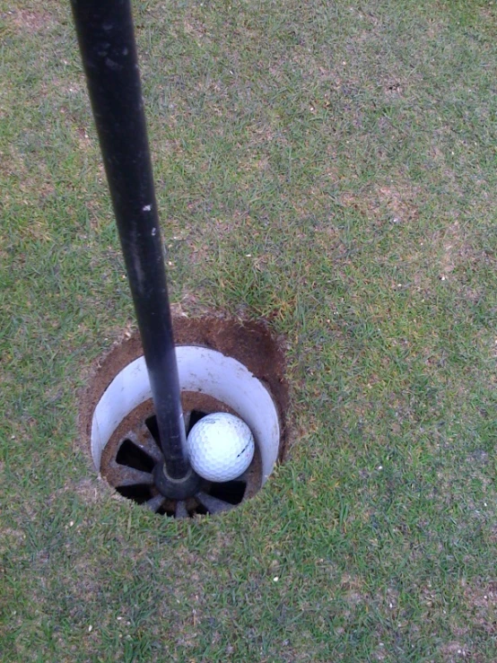 a golf ball in an open hole on the ground