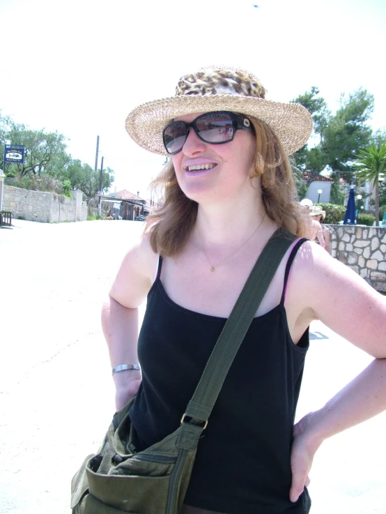 a lady wearing a hat and carrying a green purse