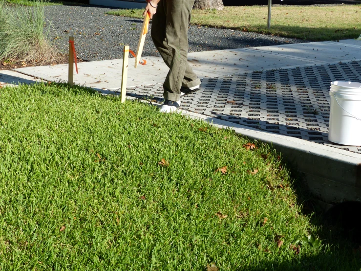 a man with a hat and umbrella is placing flowers in a flower pot on a drain hole