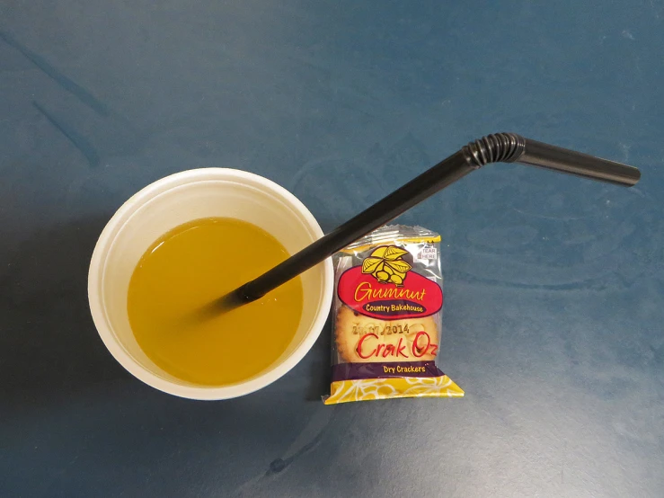 a cup of tea with a bag of chips and a black handled toothbrush
