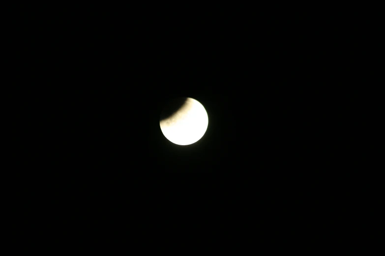 the partial moon, with a few clouds visible, appears to be very dark