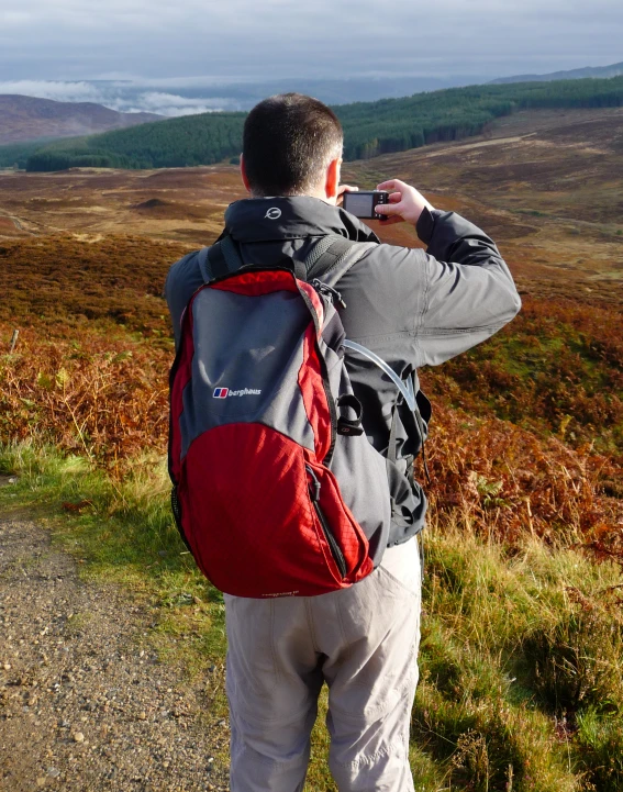 a man taking pictures while wearing a backpack