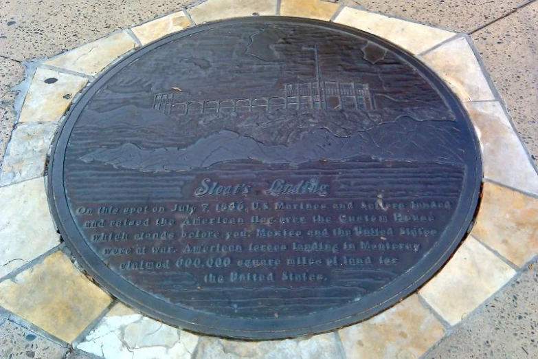 a metal plaque is on the ground on cement