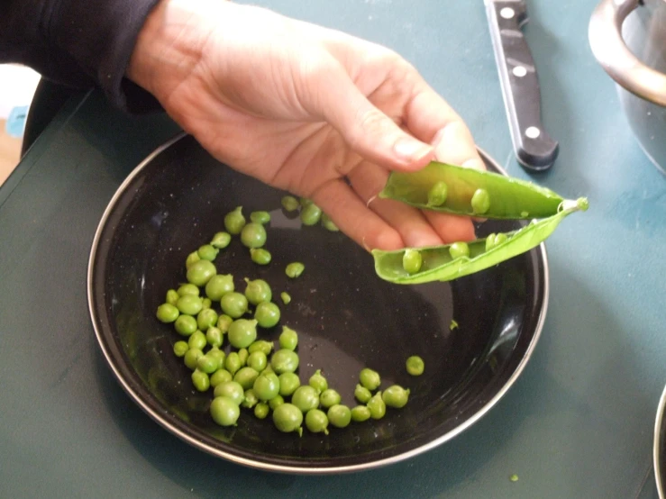 a person is preparing some peas in a pan