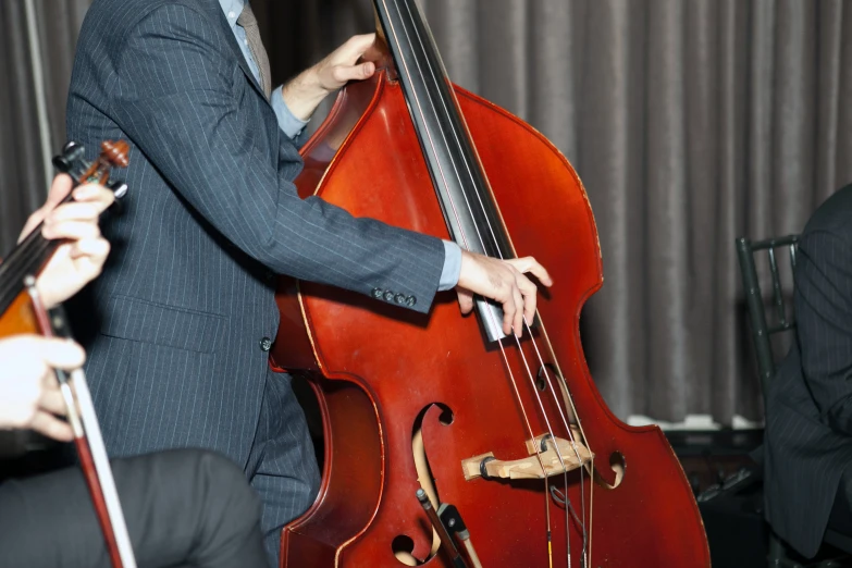 a man holding a cello playing music in a suit