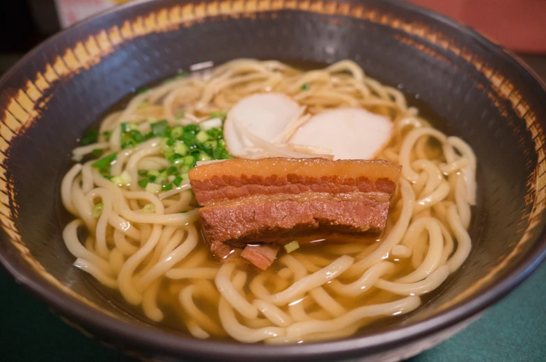 a brown and white bowl with soup and sauce and vegetables