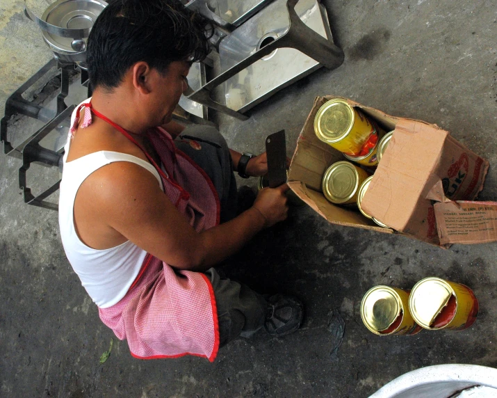 man standing over two cans of jam