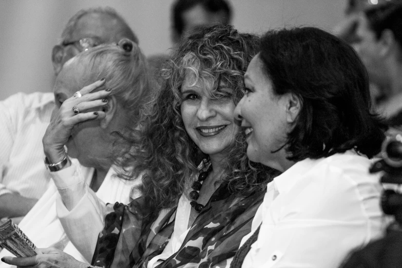 three women laugh and talk as the man looks off in the distance