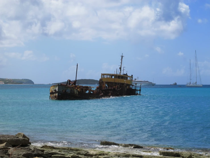 an old, rusty boat rests in the water near another ocean