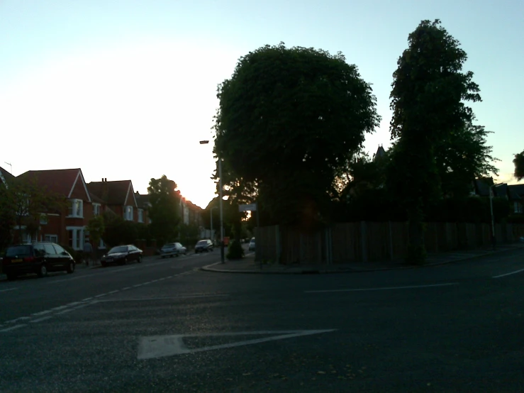 street with cars parked next to trees and a fence