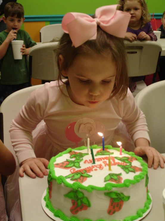 a girl sitting at a table with a birthday cake