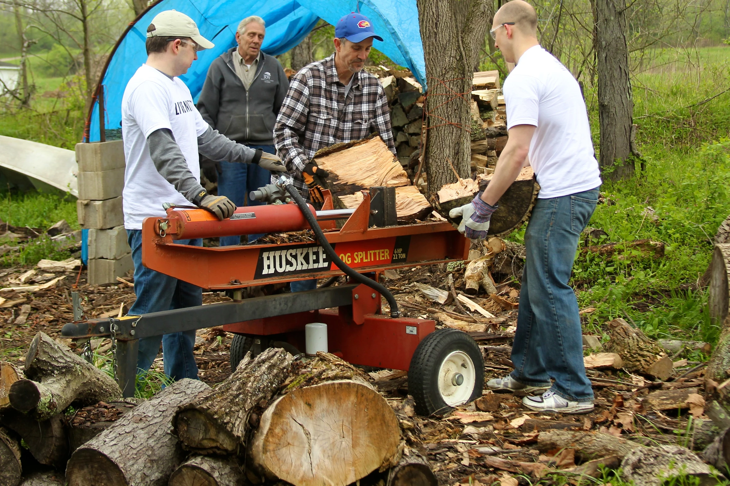 four people standing in the woods with tools