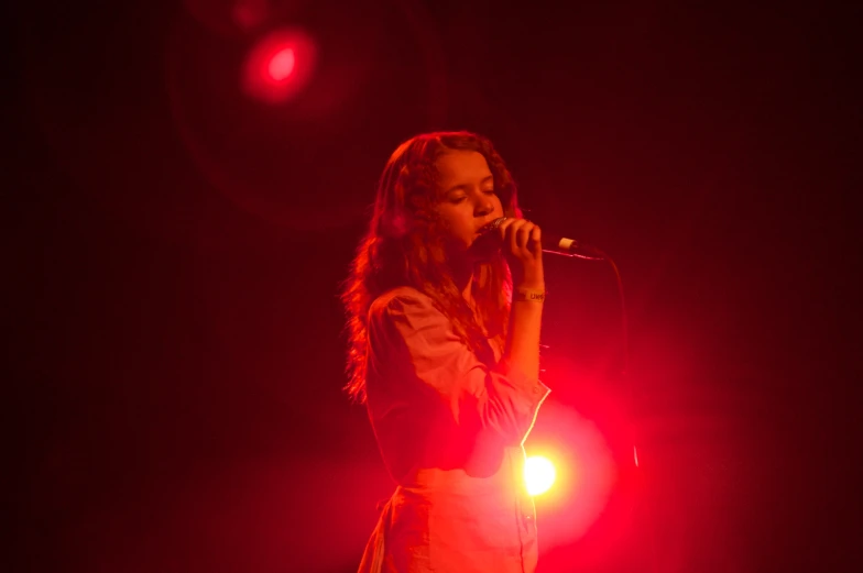 a girl with long hair on stage singing into a microphone